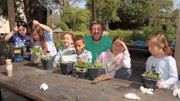 un groupe d'enfant et leur animateur montrent des pots dans lesquels ils ont fait des boutures et inséré des textes