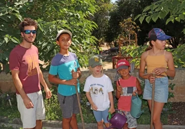 Un groupe d'enfants et leur animateur posent au jardin