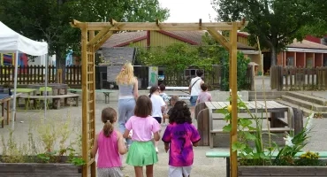 deux animatrices et 7 enfants marchent dans la cour d'un accueil de loisirs