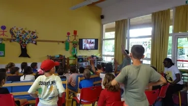 Des enfants de l'ALSH de Lavérune sont dans une salle devant un appel vidéo avec la commune de Clapiers  
