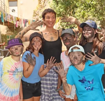 Un groupe d'enfants et leur animatrice ont le visage et les mains noirs