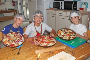 Trois enfants montrent des tartes en cuisine