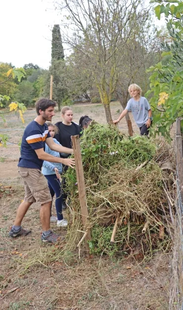 un groupe d'enfants et leur animateur mettent du bois en tas