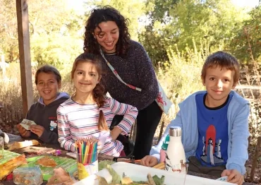 un groupe d'enfants et leur animatrice sont dehors aves des éléments naturels