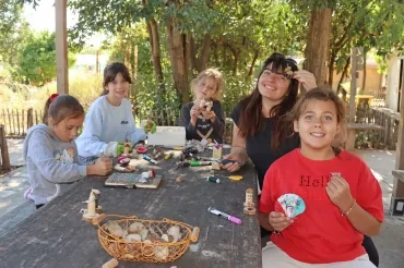 un groupe d'enfants et leur animatrice montrent leurs réalisations avec des morceaux de bois et des glands