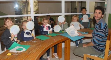 un groupe d'enfants et leur animateur montrent des cercles de papier