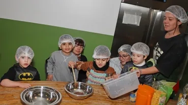 un groupe d'enfants et leur animatrice sont en cuisine avec des saladiers