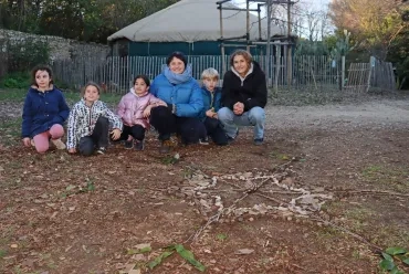 un groupe d'enfants et leurs animatrices posent devant leur réalisation en éléments naturels