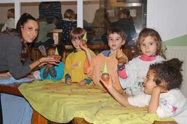un groupe d'enfants et leur animatrice montrent des boules d'argile avec un bonnet