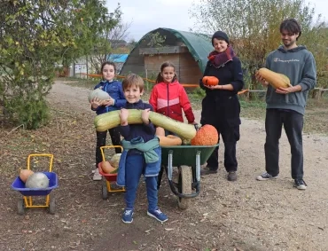 un groupe d'enfants et leurs animateurs portent des courges
