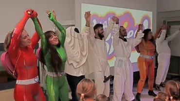 un groupe d'animateur déguisés dansent en ligne devant des enfants