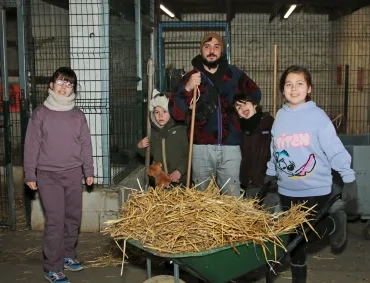 un groupe d'enfants et leur animateur posent derrière une brouette pleine de paille