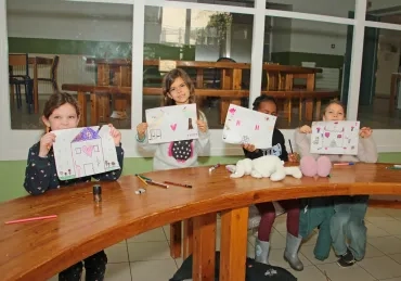 un groupe d'enfants montrent leurs dessins avec des maisons