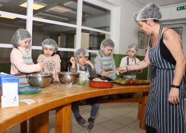 un groupe d'enfants et leur animarice remplissent des petits bols en cuisine
