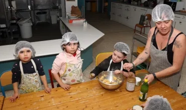 un groupe d'enfants et leur animatrice sont en cuisine avec des saladiers