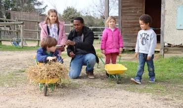 un groupe d'enfants et leur animateur mettent des choses dans de petites brouettes
