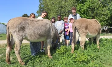 Un groupe d'enfants et leur animateur posent derrière deux ânes
