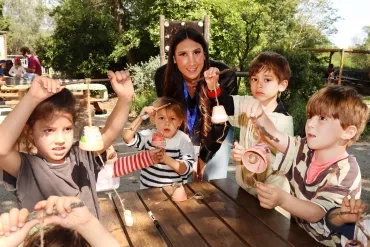 Un groupe d'enfants et leur animatrice montrent des pots en terre décorés
