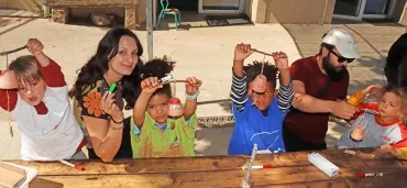 Un groupe d'enfants et leurs animateurs montrent des pots en terre décorés