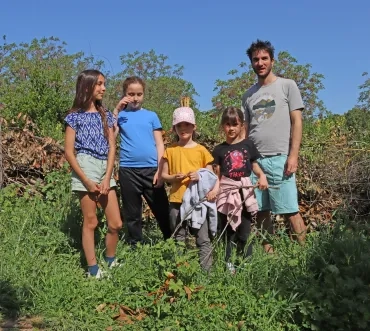 Un groupe d'enfants et leur animateur posent devant du bois mort