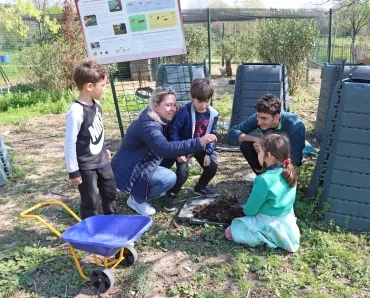 Un groupe d'enfants et leurs animateurs sont près des composteurs
