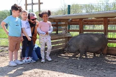 Un groupe d'enfants et leur animateur sont près d'un cochon