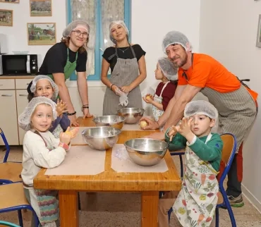 Un groupe d'enfants et leurs animateurs sont encuisine et montrent des pâtons