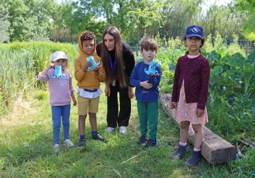 Un groupe d'enfants et leur animatrice montrent des créatures en papier