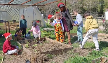 Un groupe d'enfants et leur animatrice déguisés en clowns jardinent
