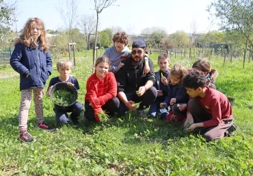 Un groupe d'enfants et leur animateur récoltent de l'herbe