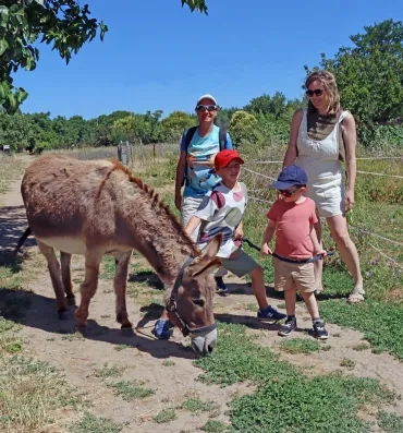 Des parents et leurs enfants promènent un âne
