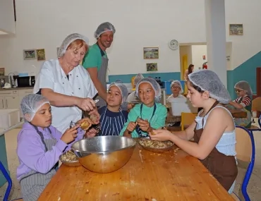 Un groupe d'enfants et leur animatrice épluchent des pommes de terre