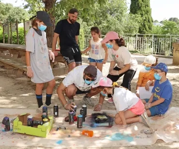 une groupe d'enfants et leurs animateurs sont accroupis avec des bombes de peinture