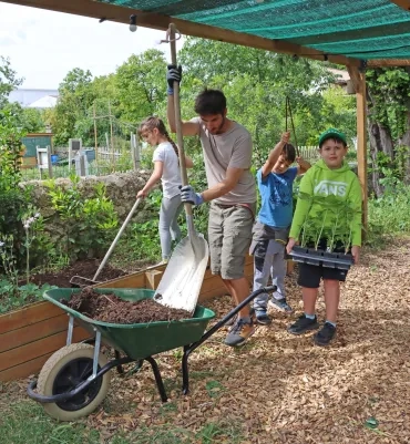 Un groupe d'enfants et leur animateur jardinent