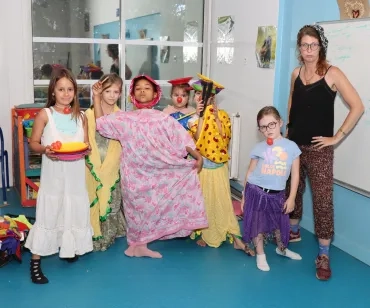 une groupe d'enfants et leur animatrice posent en costume de clowns
