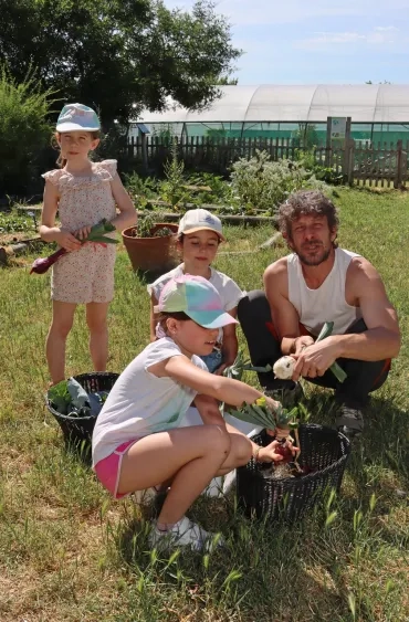 une groupe d'enfants et leur animateur récolte des oignons au jardin