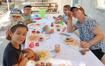 un groupe d'enfants et leur animatrice montrent leurs réalisations en terre