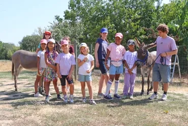 un groupe d'enfants et leur animateur posent avec deux ânes