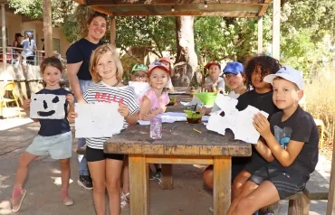 un groupe d'enfants et leur animatrice montrent des dessins