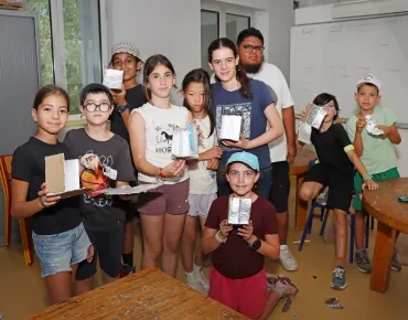 un groupe d'enfants et leur animateur montrent des morceaux de carton avec du papier aluminium