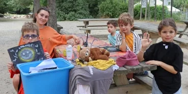 un groupe d'enfants et leur animatrice montrent des peintures