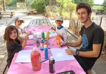 un groupe d'enfants et leur animateur peignent autour d'une table 