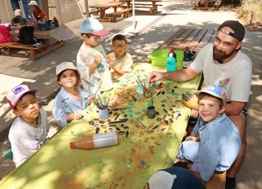 un groupe d'enfants et leur animateur peignent des morceaux de bois