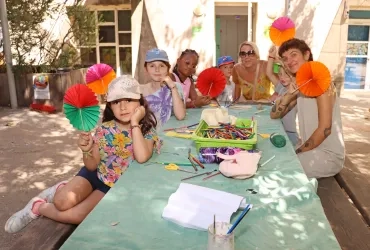 Un groupe d'enfants et leur animatrice montrent des éventails en papier