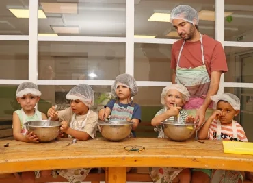un groupe d'enfants et leur animateur sont en cuisine avec des saladiers