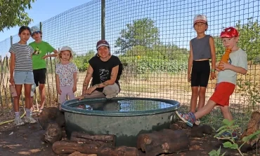Un groupe d'enfants et leur animatrice posent autour d'une grosse bassine