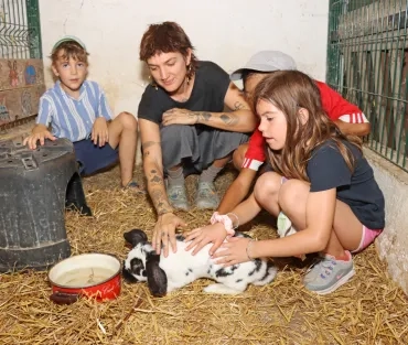 Un groupe d'enfants et leur animatrice caressent un lapin dans un enclos