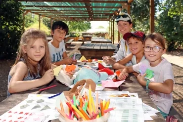 un groupe d'enfants et leur animatrice plient du papier