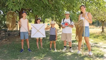 Un groupe d'enfants et leur animatrice montrent des filets à papillons et des boîtes loupes