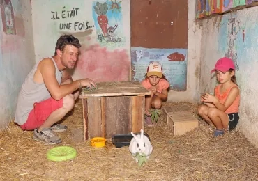 un groupe d'enfants et leur animateur donnent à manger à un lapin
